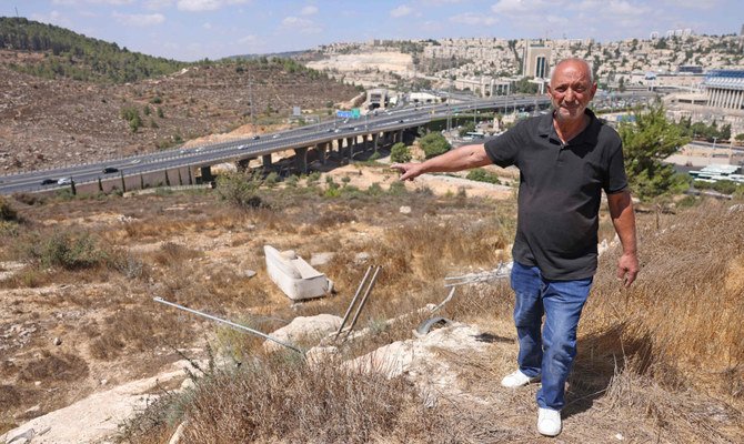 イスラエルの新入植地ギヴァット・シャケドの建設予定地を示す、アラブ人居住区ベイト・サファファのパレスチナ人住民、ファリド・サルマン氏。ギヴァット・シャケドは併合された東エルサレムでベイト・サファファと西エルサレム（背景右側）の間に位置する。2022年9月7日（AFP）