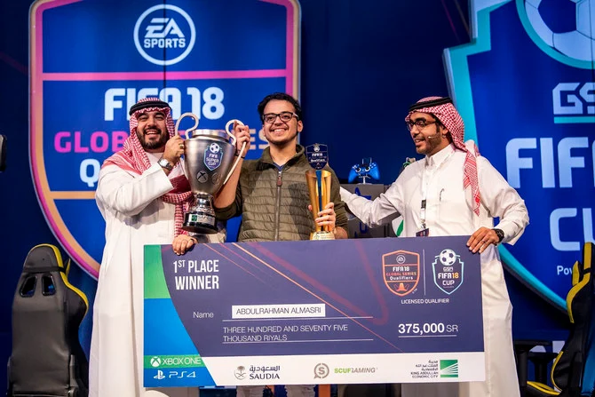 サウジeスポーツ連盟会長のファイサル・ビン・バンダル王子から優勝トロフィーと37万5000サウジリヤルの賞金を受け取る、優勝者のアブドゥルラフマン・アルマスリ氏。（提供写真）