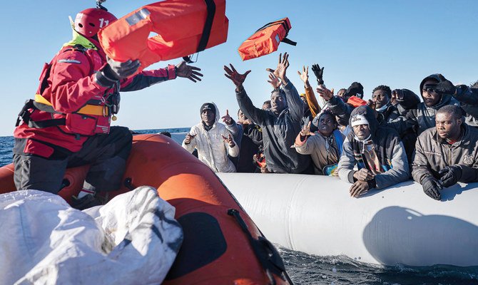 地中海を過密状態のゴムボートで漂流している移民・難民が、救援活動従事者から救命胴衣を受け取っている。（ファイル/AP）