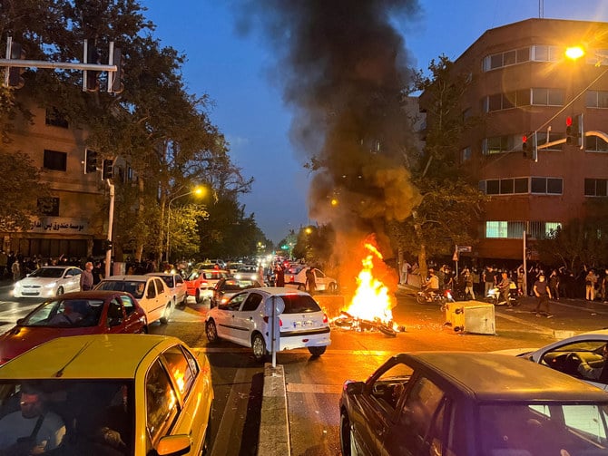 2022年9月19日、イランの「道徳警察」に逮捕された後に死亡した女性、マフサ・アミニさんの死をめぐるテヘランでの抗議活動で、警察のオートバイが燃えている様子。（WANA via REUTERS）