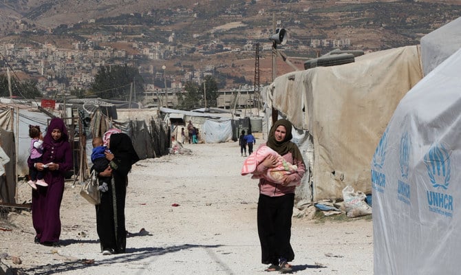 2022年10月18日、レバノンのベカー渓谷にある非公式難民キャンプで、子どもを連れて歩くシリア難民女性。（ロイター）