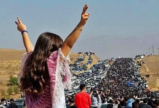 数千人もの人々が、イランのクルディスタン州にあるマフサ・ アミニさんの故郷、サッゲズのアイチ墓地に向かう中、女性がベールを纏わずに車の上に立っている。（AFP）