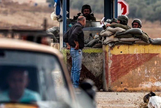 検問所のイスラエル兵に書類を手渡すパレスチナ人。占領下のヨルダン川西岸地区、ナブルス市とベイト・フリーク村の間。（AFP）