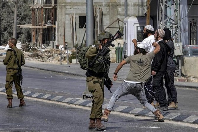 2022年10月13日、ヨルダン川西岸地区フワラで衝突が起き、イスラエル人入植者がパレスチナ人に石を投げているが、イスラエル兵は傍観している。（AFP）