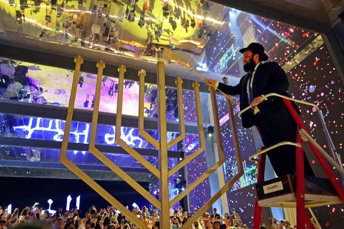 ユダヤ教の祭ハヌカーを祝って大きなメノーラーに火を灯すラビのリーバイ・ダックマン氏。2021年11月28日、ドバイ万博2020のイスラエルパビリオン。(AFP)