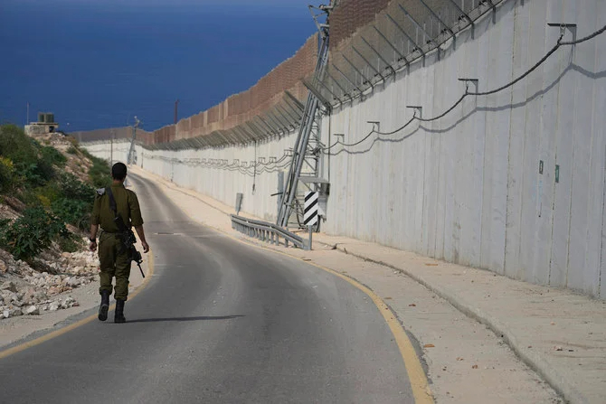 2022年10月14日（金）、イスラエルのラス・ハニクラで、イスラエル兵がイスラエルとレバノンの国境に立つ壁に沿って歩いている。（AP）