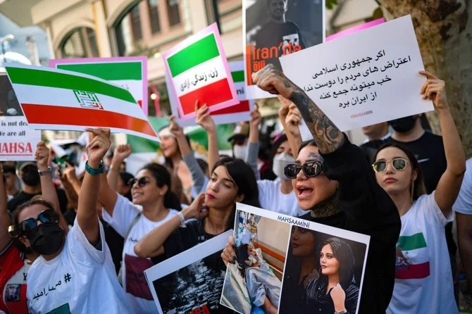 2022年9月29日、イスタンブールのイラン領事館前の集会に参加し、イラン人のマフサ・アミニ氏の肖像が描かれた横断幕を持ちながらスローガンを叫ぶデモ参加者たち。（AFP）