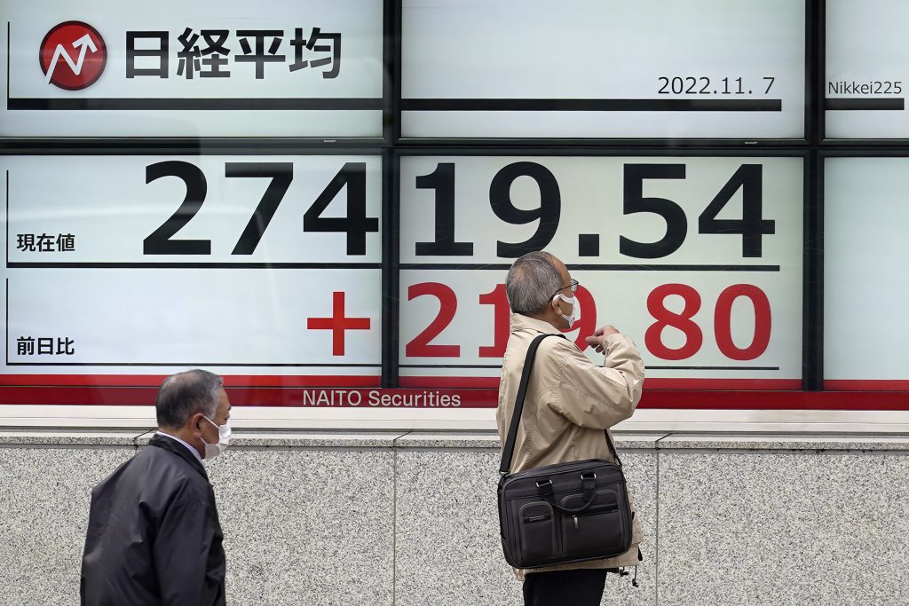 東京の証券会社で日本の日経平均株価が表示された電光掲示板の近くに立つ人々。2022年11月7日月曜日（AFP）
