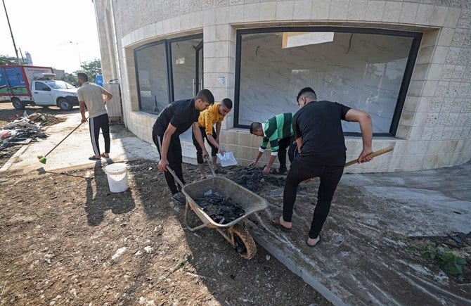 4日、ガザ地区中部にあるマガジ難民キャンプでパレスチナ人が、イスラエル軍が早朝に行った空爆の被害に遭った建物のがれきを片付けている。（AFP）