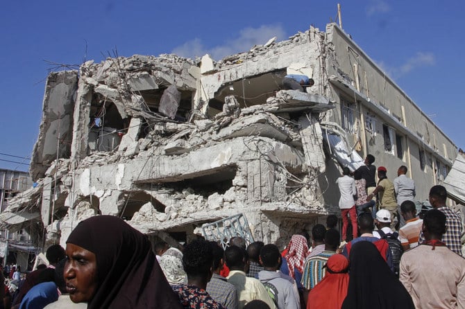 親族は破壊現場から遺体が動かされるのを待っている。ソマリア、モガディシュの交差点における2台の車による爆撃の1日後(File/AP)