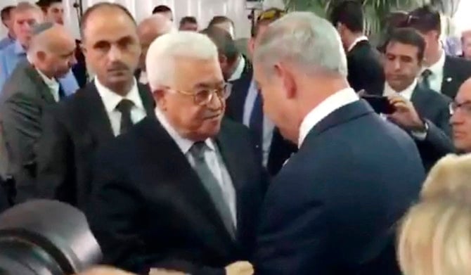 イスラエルのシモン・ペレス元首相の葬儀の際、同国のベンヤミン・ネタニヤフ首相（右）と握手するパレスチナのマフムード・アッバース大統領（中央左）。2016年9月30日、エルサレム。動画からのキャプチャー。（AFP）