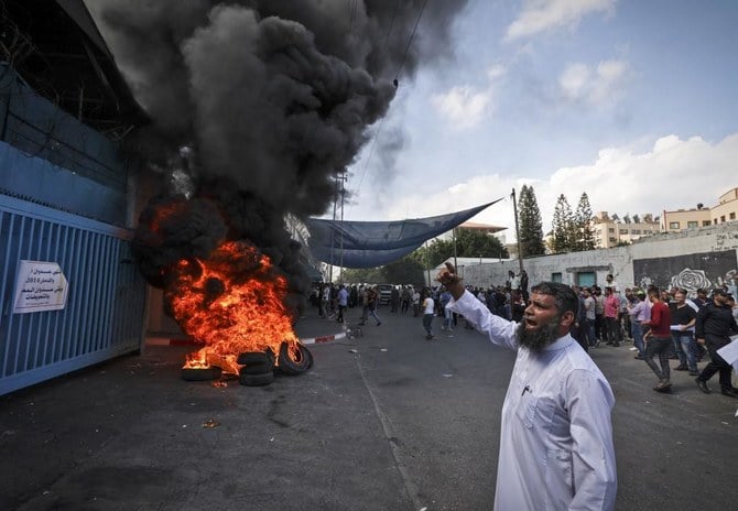 今年初め、国連パレスチナ難民救済事業機関のガザ市本部で、燃えているタイヤのそばでスローガンを唱えるデモ参加者。（AFP）