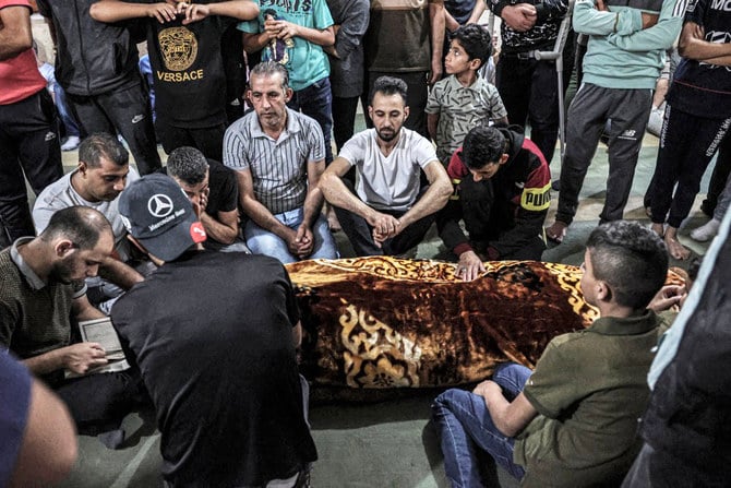 海で亡くなったパレスチナ人移民2人のうち1人の遺体の周りに集まって悲しむ人々。（AFP）