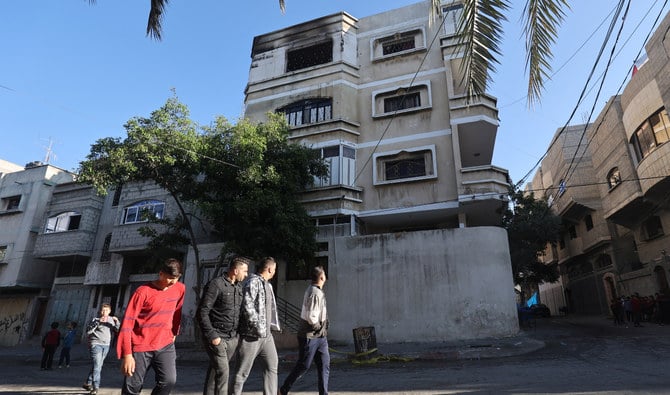 ガザ地区北部のジャバリア難民キャンプで、パレスチナ人男性たちが建物の前を通り過ぎている。前日、この建物の最上階にあるアパートで火事が起きた。(2022年11月18日撮影)(AFP)