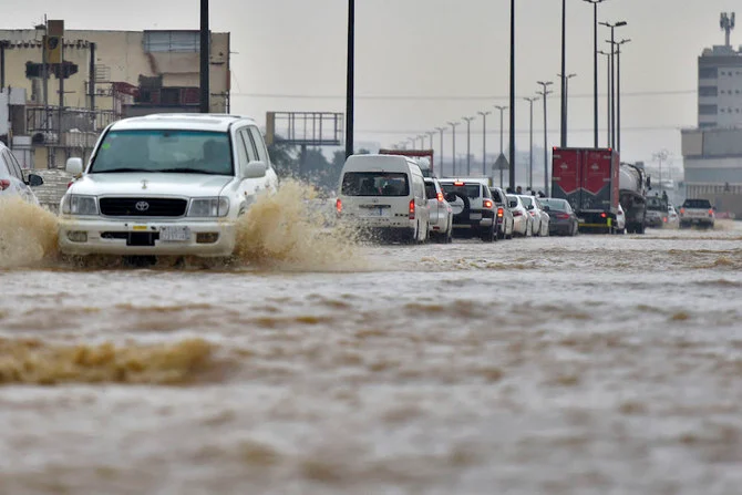 2022年11月24日、ジェッダで大雨が降り、フライトが遅れ、学校が休校となり、メッカに通じる道路が閉鎖された後、冠水した道路を走る車。（AFP）