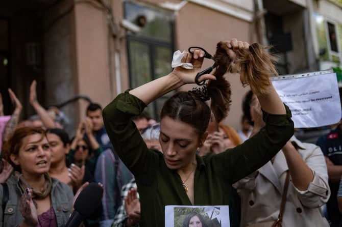 イスタンブールのイラン領事館前での抗議行動中にポニーテールを切り落とすトルコ在住のイラン人女性、ナシベ・サムサイさん。(ファイル/AFP)