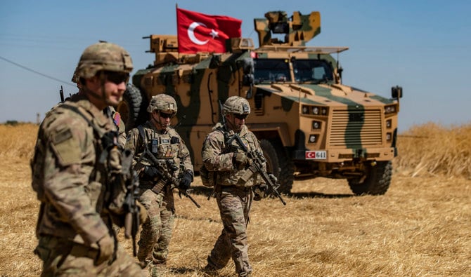 2019年9月8日、トルコ軍との国境沿いのタルアビヤド町郊外で、トルコ軍との合同パトロール中にトルコ軍車両の前を歩く米軍兵士。（AFP/ファイル）