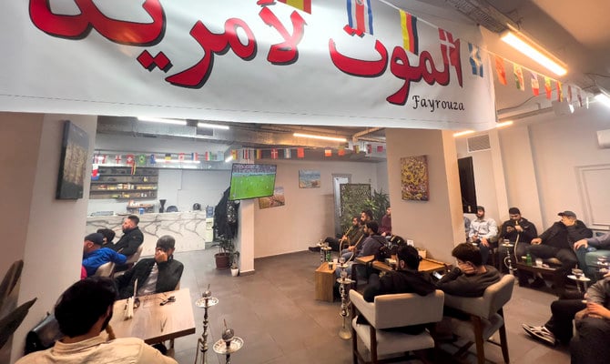 アラビア語で「米国に死を」と書かれた横断幕の下に座ってワールドカップ・グループBの米イラン戦を観戦する、レバノンのイランチームファンたち。2022年11月29日（火）、レバノンのベイルート南郊のコーヒーショップ。（AP）