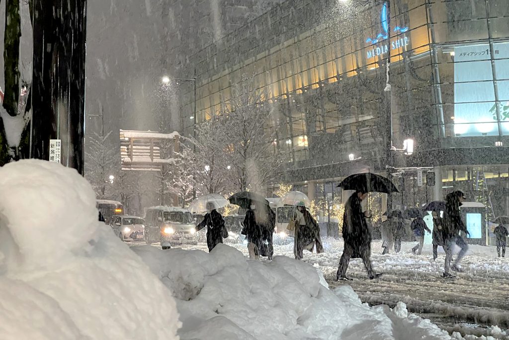 気をつけて道路を渡る人たち。2022年12月19日、北日本にある新潟市は大雪に見舞われた。（AFP）
