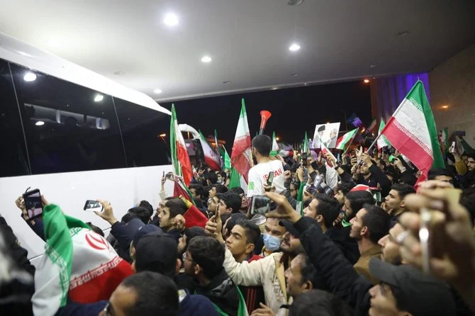 カタールでのワールドカップ2022に出場して帰国したイラン代表チームを出迎えるため、テヘランのエマーム・ホメイニ空港に集まったイランのファンたちが旗を振っている様子。（AFP）