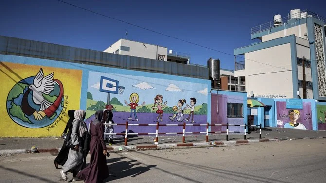 2022年12月1日、ガザ市にて国連パレスチナ難民救済事業機関（UNRWA）が運営する学校の前を歩く女性たち。（AFP）