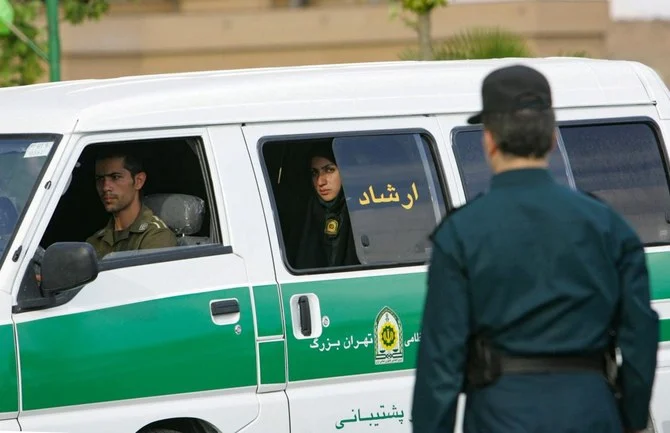 イスラムの服装規定を強制するための取り締まりを始める前に警察車両の後部座席から見張るイランの女性警察官。首都テヘラン。（ファイル/AFP）