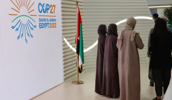 COP27気候サミットの会期中、エジプトの紅海に面したリゾート都市シャルムエルシェイクのシャルムエルシェイク国際コンベンションセンターに掲げられたCOP27を告知する看板の前を歩くムスリムの女性。2022年11月15日（AFP）