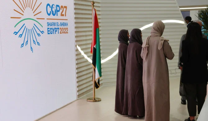 COP27気候サミットの会期中、エジプトの紅海に面したリゾート都市シャルムエルシェイクのシャルムエルシェイク国際コンベンションセンターに掲げられたCOP27を告知する看板の前を歩くムスリムの女性。2022年11月15日(AFP)