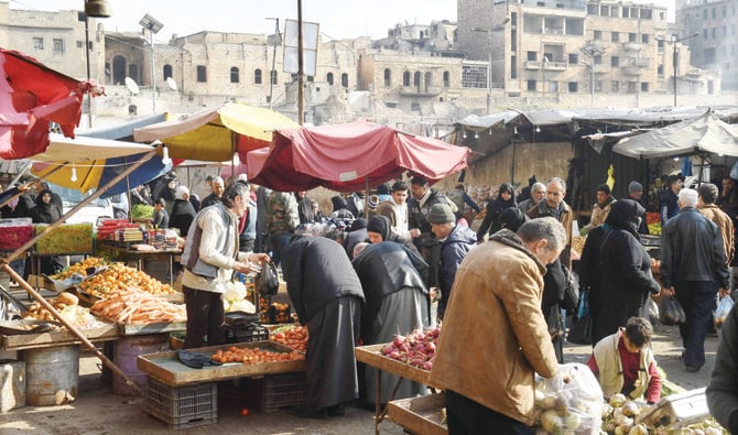 シリア政権の支配下にある北部の都市アレッポの市場で買い物をする人々。（AFP）
