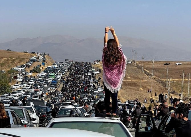 2022年10月26日にツイッターに投稿されたとされる、ユーザーが撮影した画像に映っているのは、車の屋根の上に立つ、ヒジャブを脱いだ女性だ。数千人の人たちが、マフサ・アミニさんの死後40日の追悼を行うために、アミニさんの故郷であるイラン西部クルディスタン州サゲズにあるアイチ墓地に向かっている。（AFP）