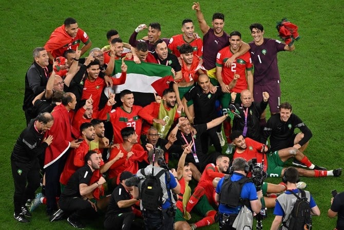 スペインに劇的な勝利を収めた後にパレスチナの旗を示すモロッコの選手たち。（AFP）