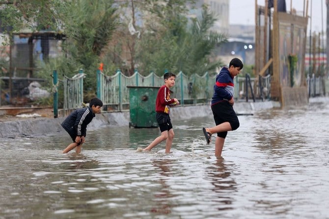 2022年12月24日、大雨で冠水したイラクの首都バグダッドの道路を横断するイラクの子どもたち。(AFP)