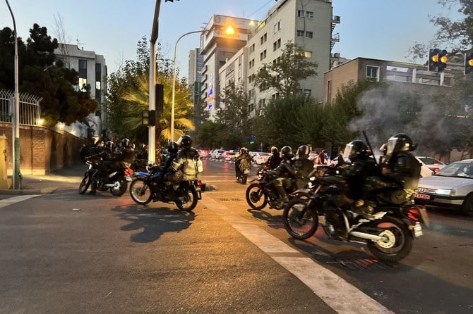 テヘランでマフサ・アミニさんを支持する抗議運動の中、バイクに乗ったイランの警察官が見える。（ファイル／AFP）