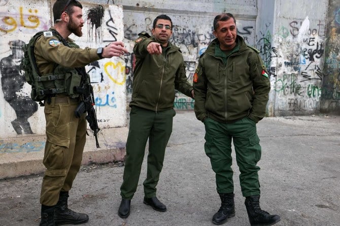 2022年12月24日、ヨルダン川西岸地区の占領地ベツレヘムで、パレスチナ人治安部隊の隊員と談笑するイスラエル兵（左）（ファイル写真／AFP通信）