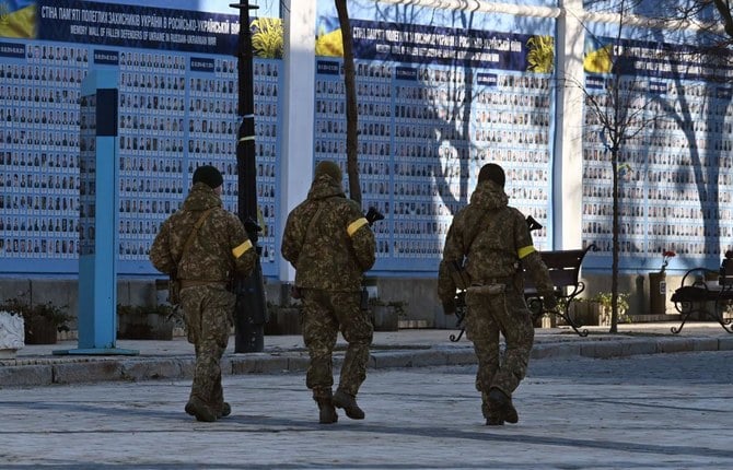 ロシアによるウクライナ侵攻のさなか、ウクライナのために亡くなった人々の追悼の壁に沿って歩くウクライナ軍兵士。（AFP）