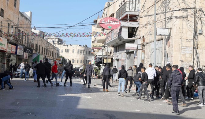 イスラエル治安部隊との衝突が発生する中、パレスチナ人が集まり抗議している。2022年12月30日、占領地ヨルダン川西岸地区のナブルス旧市街で急襲作戦が行われており、治安部隊が展開している。（AFP）
