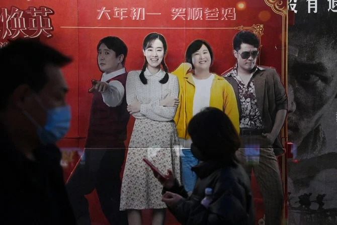 映画「こんにちは、私のお母さん」の看板の前を通り過ぎる人々。2021年2月22日、北京の映画館の外。中国の映画館には、この感傷的なコメディ映画を見ようと観客が詰めかけている。ジア・リン監督のこの映画は短期間で中国史上最も多くの観客を集めた映画の一つとなり、この女性監督にとって華々しいデビューとなった。（ファイル/AFP）