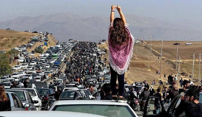 イランのマフサ・アミニさんの地元に数千人が向かう中、自動車の上に立つ女性。(AFP)