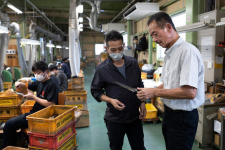 2022年9月2日撮影、岐阜県関市の工場で包丁の品質を確認するスミカマ代表の炭竈勝美氏(右)。(AFP)