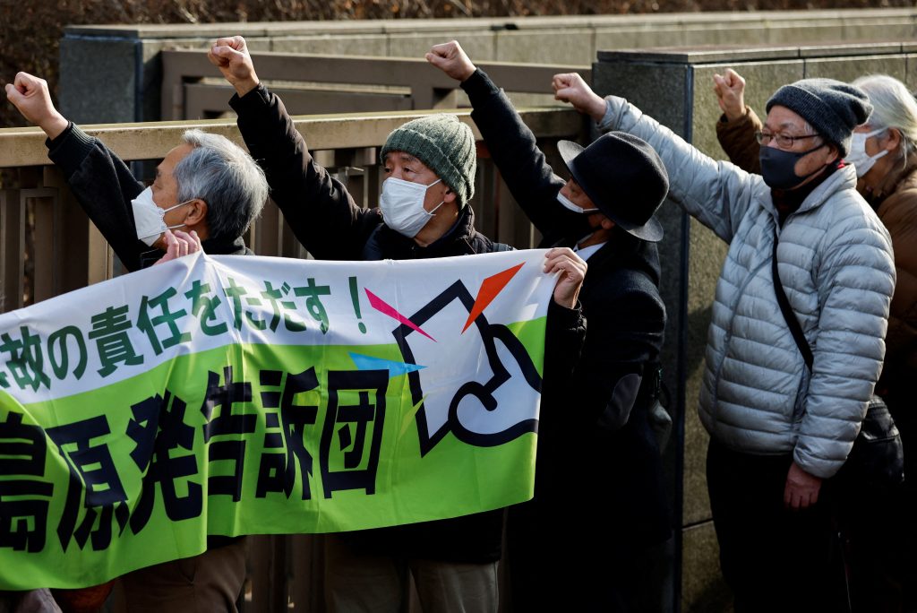 2023年1月18日、東京電力福島第一原子力発電所の事故をめぐり、東京高裁が東京電力元幹部の無罪判決を支持したことを受け、東京都内の裁判所前にて、こぶしを上げてスローガンを叫ぶ原告の支援団体メンバーら。(ロイター/Issei Kato)