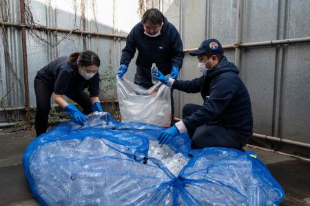 東京都足立区の白井エコセンターで、プラスチック汚染問題を訴える革新的なバレエ公演、「プラスチック」の衣装やセットに使用するため、ペットボトルを分別する人たち。(2022年11月12日撮影 AFP)