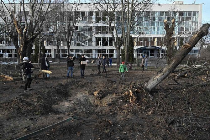 2023年1月1日、キーウにある教育施設の横にできた穴を見る人たち。ロシアによるウクライナ侵攻が続く中、この教育施設は前日、ミサイル攻撃で損傷を受けた。（AFP）