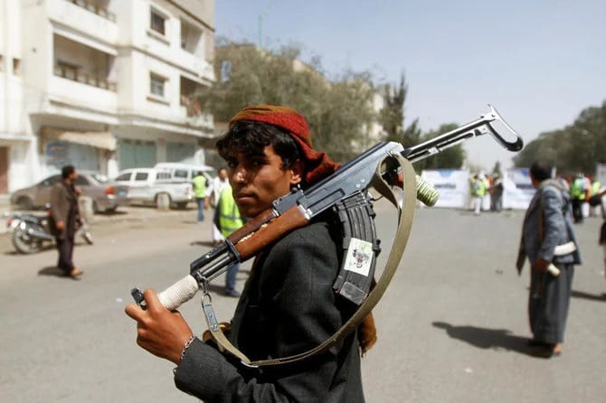 サヌアで集会が開かれているときに、武器を持ったフーシ派の支持者がこちらを見ている。（ロイター/資料写真）