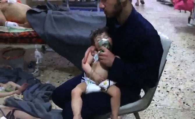 ドゥーマのシリア市民防衛隊が公開した動画からのスクリーンショット。2018年4月8日、反政府勢力が支配した町への化学兵器攻撃が報告された後、未確認のボランティアが病院で子どもの顔に酸素マスクをかぶせる様子。（AFP/資料写真）