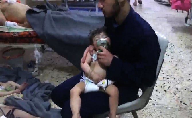 ドゥーマのシリア市民防衛隊が公開した動画からのスクリーンショット。2018年4月8日、反政府勢力が支配した町への化学兵器攻撃が報告された後、未確認のボランティアが病院で子どもの顔に酸素マスクをかぶせる様子。(AFP/資料写真)