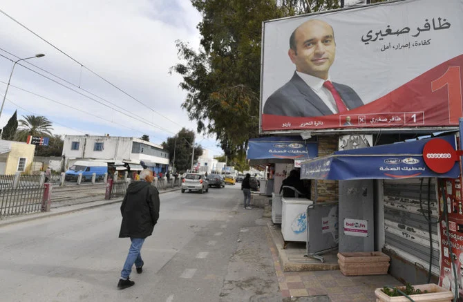 2023年1月25日、チュニジアの首都チュニスで、1月29日に予定されているチュニジア国政選挙の選挙看板の前を歩く男性。 (AFP)
