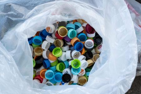 東京都足立区の白井エコセンターで、プラスチック汚染問題を訴える革新的なバレエ公演、「プラスチック」の衣装やセットに使用するため、ペットボトルのキャップを分別する人々が、リサイクル用に取っておいた数百個のボトルキャップの袋。(2022年11月12日撮影 AFP)