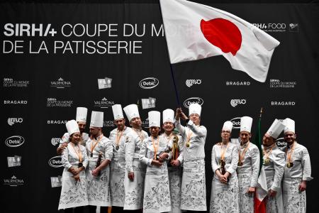 2023年1月21日、フランス南東部リヨン近郊のシャッシューエクスポ会場で開催されたシラ(SIRHA)(国際外食産業見本市、ホスピタリティとフード Salon International de la Restauration, de l'Hôtellerie et de l'Alimentation) で行われた「2023ボキューズ・ドール・パティスリー・コンクールBocuse d'Or pastry competition」の表彰台で喜ぶ1位の日本(中央)、2位のフランス(左)、3位のイタリア。(AFP)