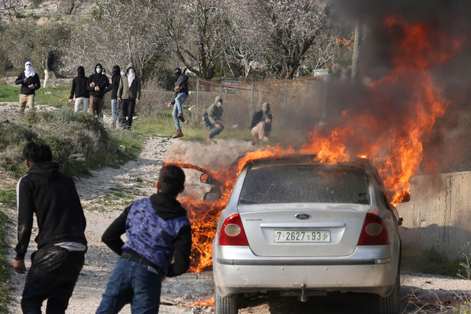 車に放火した入植者ら（奥）に向かって投石するパレスチナ人の若者ら。2023年2月25日、ブリン村。（AFP）