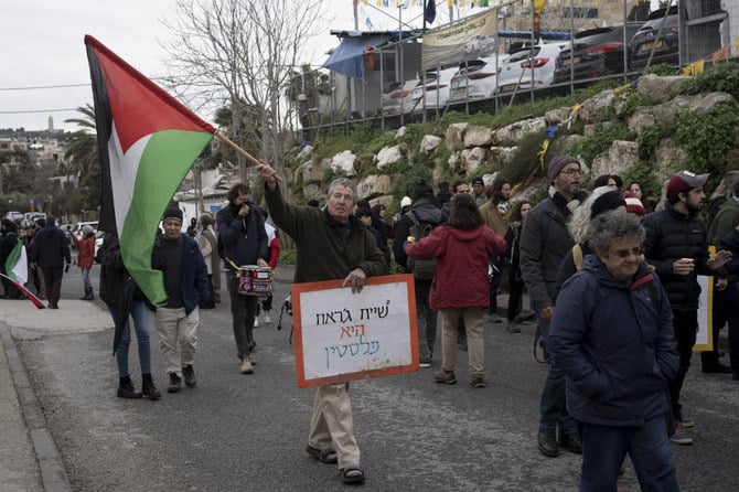 包囲されたシェイク・ジャラー地区に住むパレスチナ住民たちとの連帯の意思を示すため、パレスチナ人、イスラエル人、その他外国人らによって週に一度行われるデモ運動で、2023年2月3日、パレスチナの旗と「シェイク・ジャラーはパレスチナのものだ」と書かれたプラカードを掲げるデモ参加者。（AP）